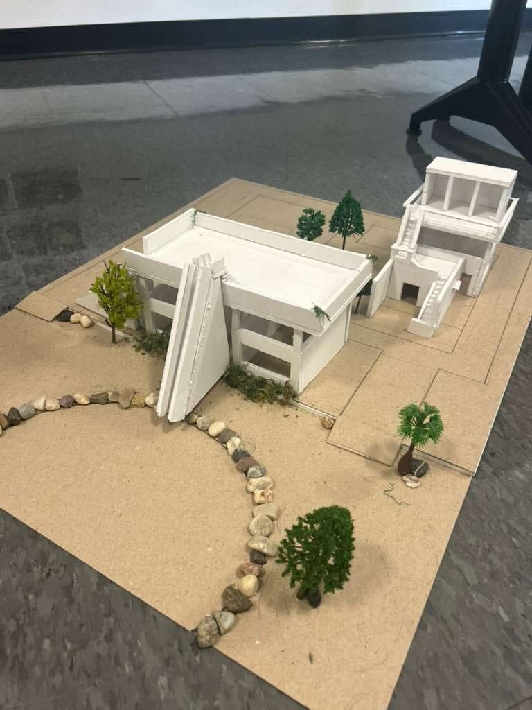 White architectural model of a house with model trees on a cardboard base